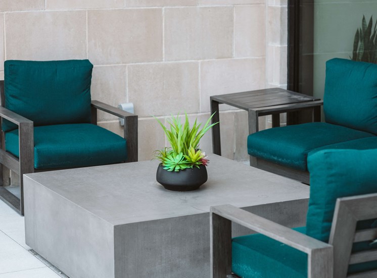 outdoor seating area with 3 blue lounge chairs around a square gray table